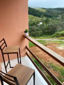 a table and chair on a balcony with a view at Recanto da Paz Ibitipoca com Hidromassagem in Conceição da Ibitipoca