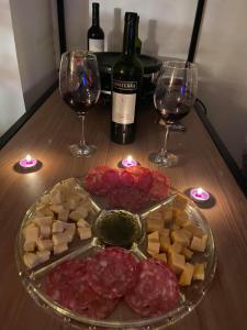 a table with a plate of meats and wine glasses at Recanto da Paz Ibitipoca com Hidromassagem in Conceição da Ibitipoca