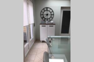 ein Raum mit einem Glastisch und einer Uhr an der Wand in der Unterkunft La maison d'Adélie in Bourbourg