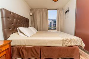 a bedroom with a large bed with a window at Departamentos Alpro Cavancha in Iquique