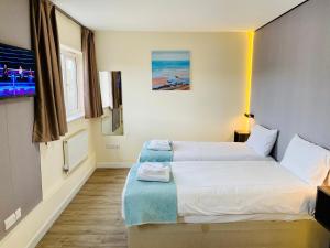 a hotel room with two beds and a television at Almond Tree Hotel in Bicester