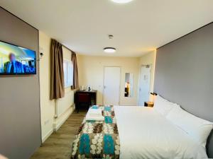 a bedroom with a large bed and a flat screen tv at Almond Tree Hotel in Bicester