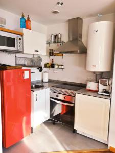 eine Küche mit weißen Schränken und einem roten Kühlschrank in der Unterkunft Beachport in Viveiro