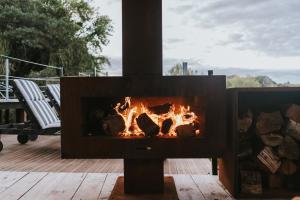 羅托魯阿的住宿－Oakridge Glamping，壁炉在甲板上,壁炉里放着火