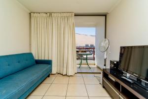 salon z niebieską kanapą i telewizorem w obiekcie Alpro Urbano Oriente w mieście Iquique