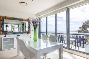a white dining room with a vase of flowers on a table at Geelong Waterfront Penthouse Apartment in Geelong