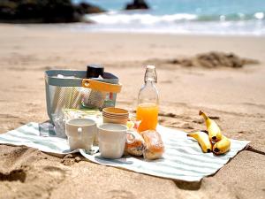 um piquenique na praia com uma cesta de comida e sumo de laranja em Oli Oli Guesthouse em Shimoda
