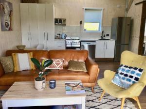 a living room with a brown leather couch and a kitchen at Warkworth Barn Retreat in Warkworth