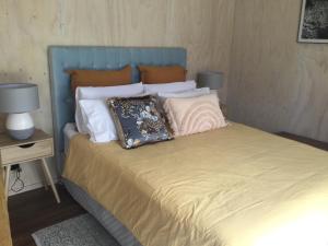 a bed with a blue headboard and pillows on it at Warkworth Barn Retreat in Warkworth