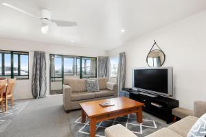 a living room with a couch and a tv at Mount Sunset - Mt Maunganui Townhouse in Mount Maunganui