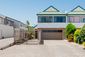 a house with a gate in front of a driveway at Mount Sunset - Mt Maunganui Townhouse in Mount Maunganui