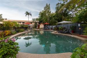 a swimming pool with blue water in a yard at Lychee Tree Holiday Apartments in Port Douglas