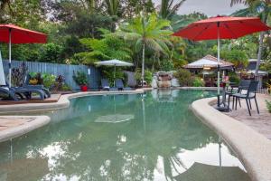 a patio area with a pool, chairs, and a fountain at Lychee Tree Holiday Apartments in Port Douglas