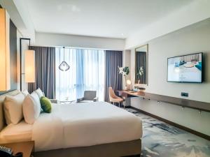 um quarto de hotel com uma cama grande e uma secretária em The Excelsior Hotel Las Piñas em Manila