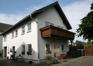 ein weißes Haus mit einem Holzbalkon darauf in der Unterkunft Ferienhaus Ginsterblüte in Schleiden