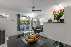 a table topped with a bowl of fruit next to a window at Lychee Tree Holiday Apartments in Port Douglas