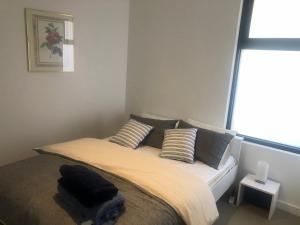 1 dormitorio con cama con almohadas y ventana en C-Scape Penthouse - Cowes beach front en Cowes