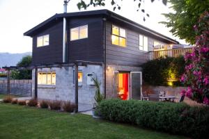 a black house with a red door in a yard at Number 10 Arrowtown Sleeps 12 in Arrowtown