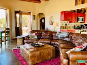 a living room with a leather couch and a kitchen at The Casita del Lago in Abiquiu
