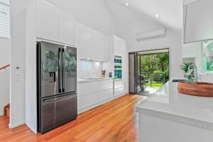 a kitchen with white cabinets and a stainless steel refrigerator at Naturally majestic, Noosa Heads in Noosa Heads