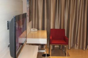 a red chair sitting next to a desk with a television at Pride Elite, Phaltan in Phaltan
