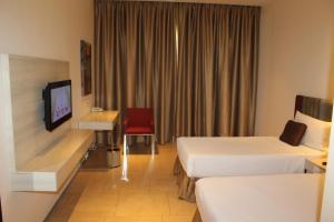a hotel room with two beds and a television at Pride Elite, Phaltan in Phaltan +64 photos