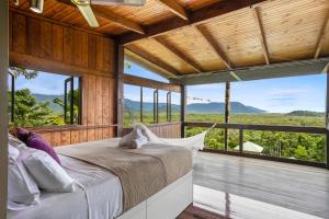 a bedroom with a bed on a balcony with windows at Daintree Holiday Homes - La Vista in Cow Bay