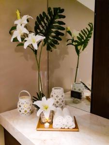 - un comptoir de salle de bains avec des fleurs blanches dans un miroir dans l'établissement The Excelsior Hotel Las Piñas, à Manille