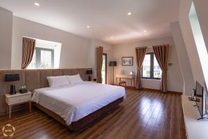 a bedroom with a large white bed and wooden floors at Hotel Du Ciel in Da Lat