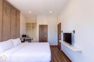 a bedroom with a white bed and a flat screen tv at Hotel Du Ciel in Da Lat