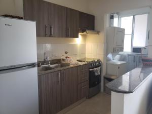 - une cuisine avec des placards en bois et un réfrigérateur blanc dans l'établissement Elegante apartamento discreto, con playa y piscina, à Bique