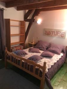 a bedroom with a wooden bed with purple pillows at Jolie Gîte dans les Pyrénées in Boutx +1 photo