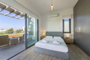 a bedroom with a large bed and a balcony at Pernera Beach Villa in Protaras +32 photos