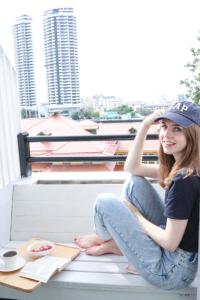 a young girl sitting on a bench with a table at Khaosan Art Hotel in Bangkok