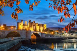 a castle on a bridge over a body of water at The North Wales Gathering - 9 Bedroom - EV Charging in Flint