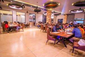 een groep mensen die aan tafel zitten in een restaurant bij The Bhagwati Resort in Abu Road
