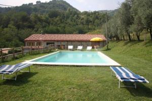 einen Pool mit zwei Stühlen und ein Haus in der Unterkunft casa vacanze in Garfagnana in Gallicano