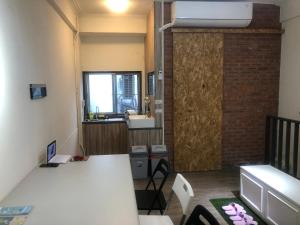 a room with a desk and a kitchen with a window at Simple Walk Guest House 小公寓 in Tainan