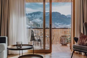 a living room with a balcony with a view of a mountain at PoSt Boutique Apartments in Maria Alm am Steinernen Meer