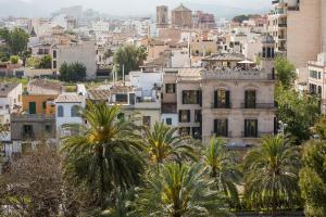 an old building with palm trees in front of a city at Loft en Santa Catalina in Palma de Mallorca