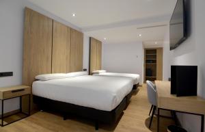 a bedroom with two beds and a flat screen tv at UVE Marcenado in Madrid