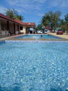 uma piscina com água azul em frente a uma casa em Faris's Homestay & Resort em Pasir Puteh