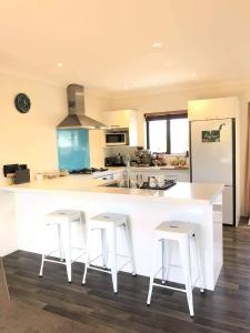 a kitchen with a large white counter and stools at Mangawhai Room in Mangawhai