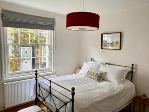 a bedroom with a bed and a red lamp at Picturesque Seaside Cottage Next to Viking Bay - Broadstairs in Broadstairs