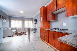 cocina con armarios de madera y sala de estar. en Khayalami Hotel - Emalahleni, en Witbank