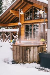 a wooden cabin with a hot tub in the snow at Puruvesi Holiday Villas, Riuttahovi in Hiukkajoki