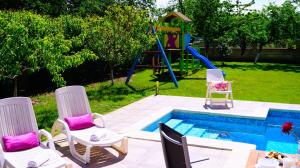 a group of chairs and a pool with a playground at Вила Релакс - Villa Relax in Sokolovo