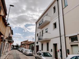 a white building on a street with parked cars at Montenero - B in Olbia