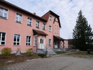 a large pink house with a tree in front of it at Touristisches Begegnungzentrum Melchow in Melchow