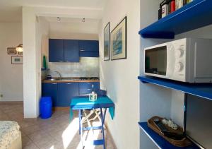 a kitchen with blue cabinets and a blue table and a microwave at Lilli's House in Porto Santo Stefano +8 photos